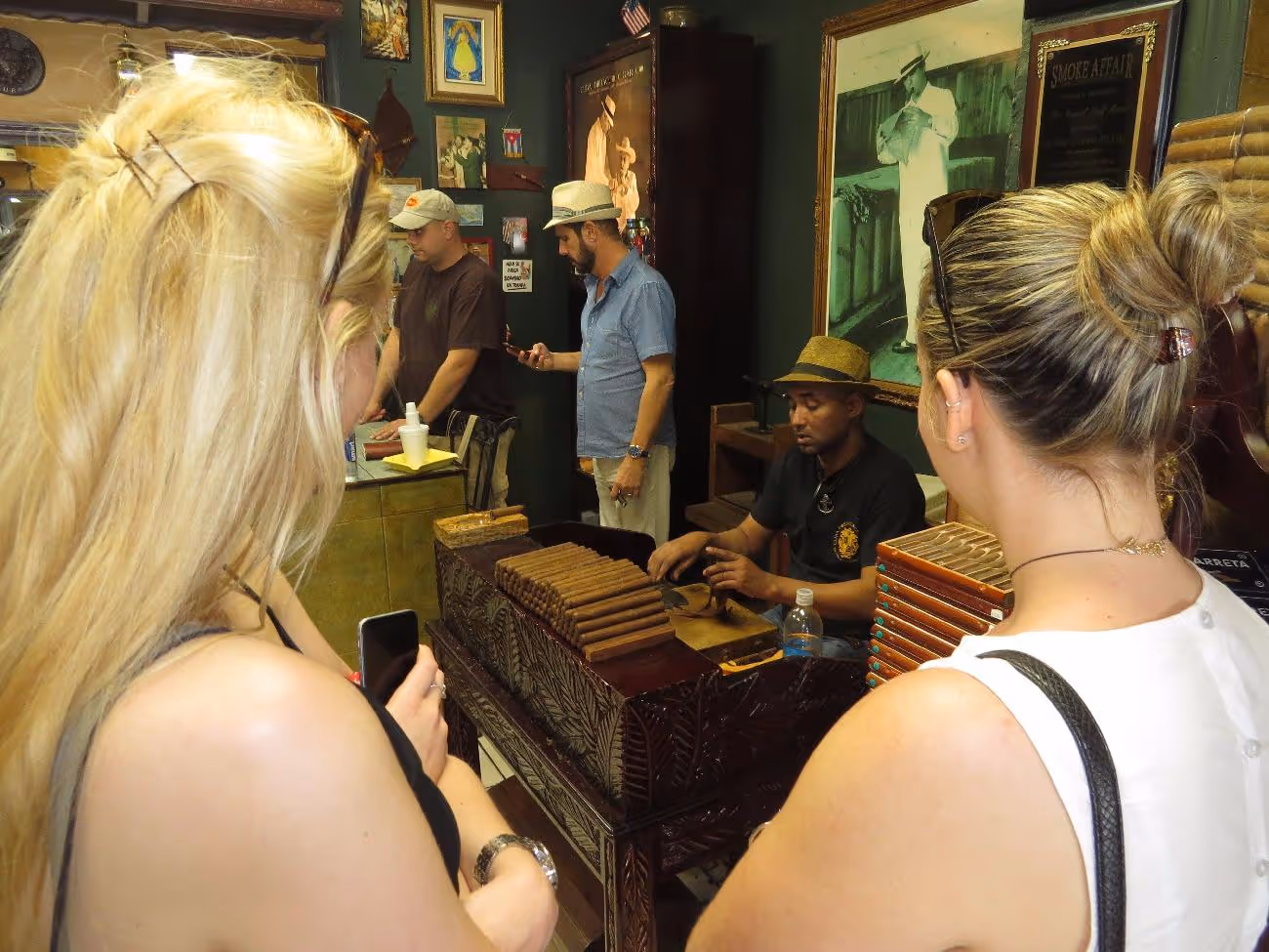 Young ladies watching a man hand-roll cigars