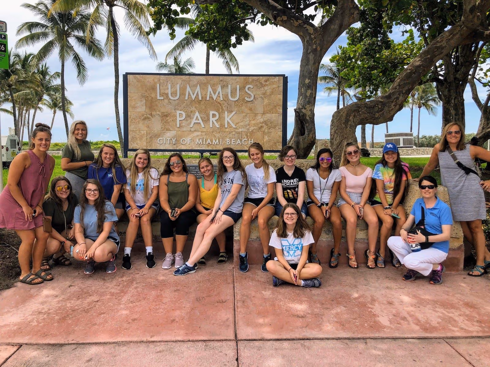 High school students posing near the Lummus Park sign on Ocean Drive