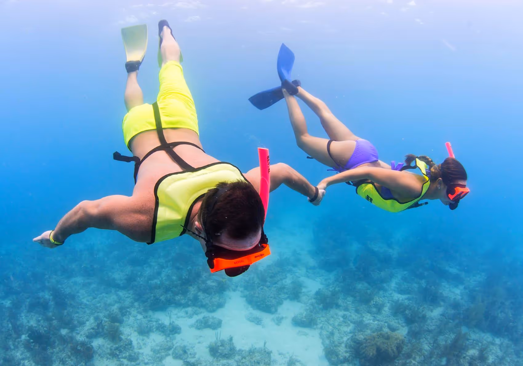 Young couple snorkeling underwater holding hands