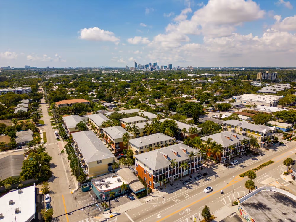 A city street with apartment buildings and a car driving down it.