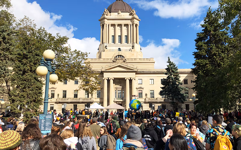 A large group of people gathered in front of a building with a globe on top.