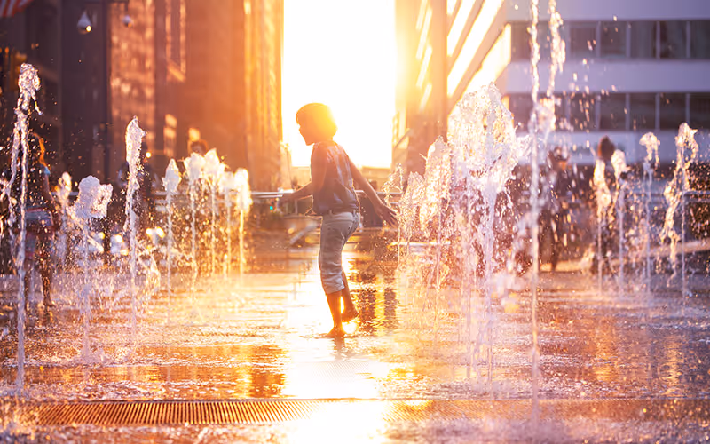 A young girl is walking through a fountain.