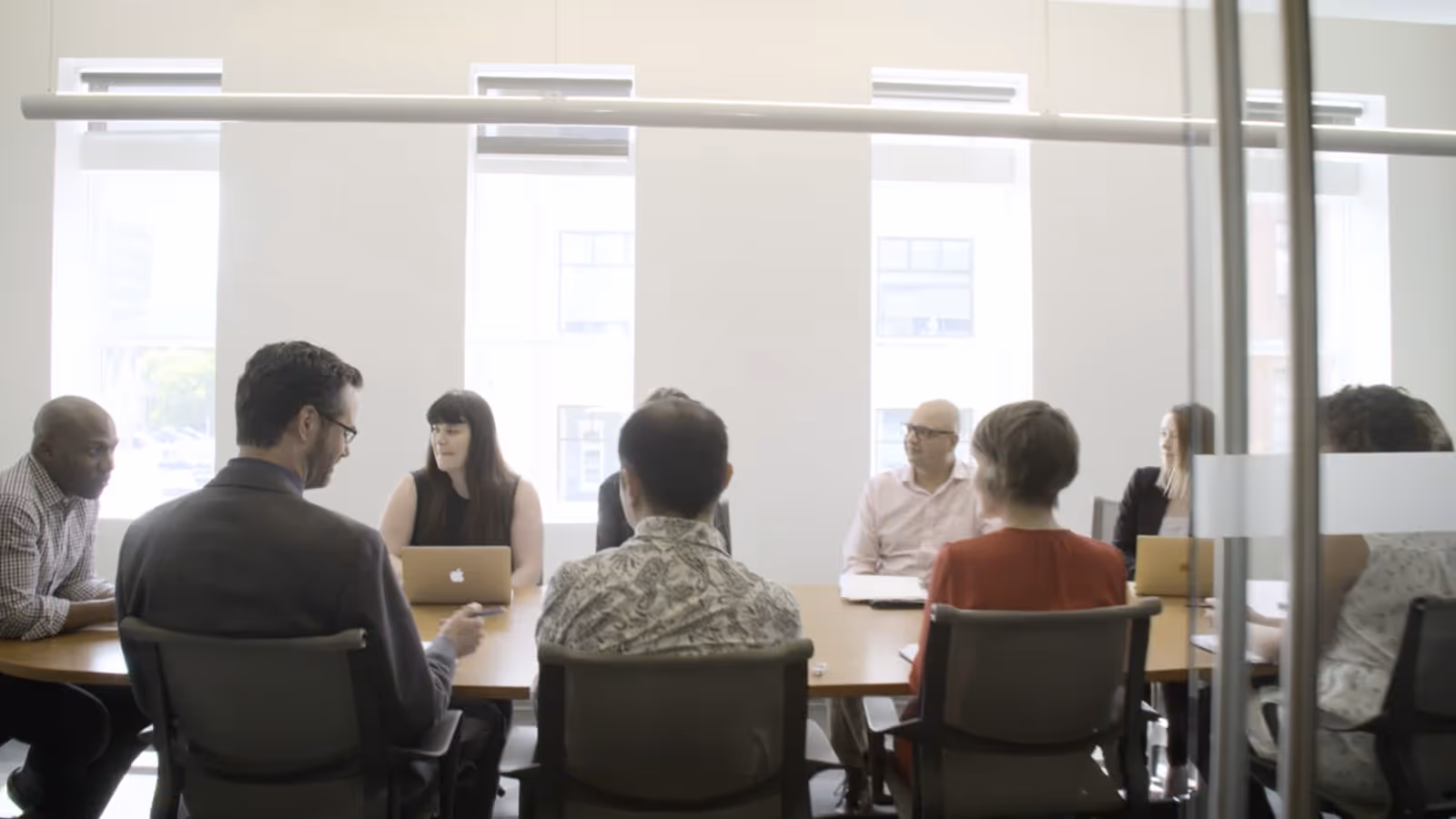 A group of people sitting around a table with a laptop.