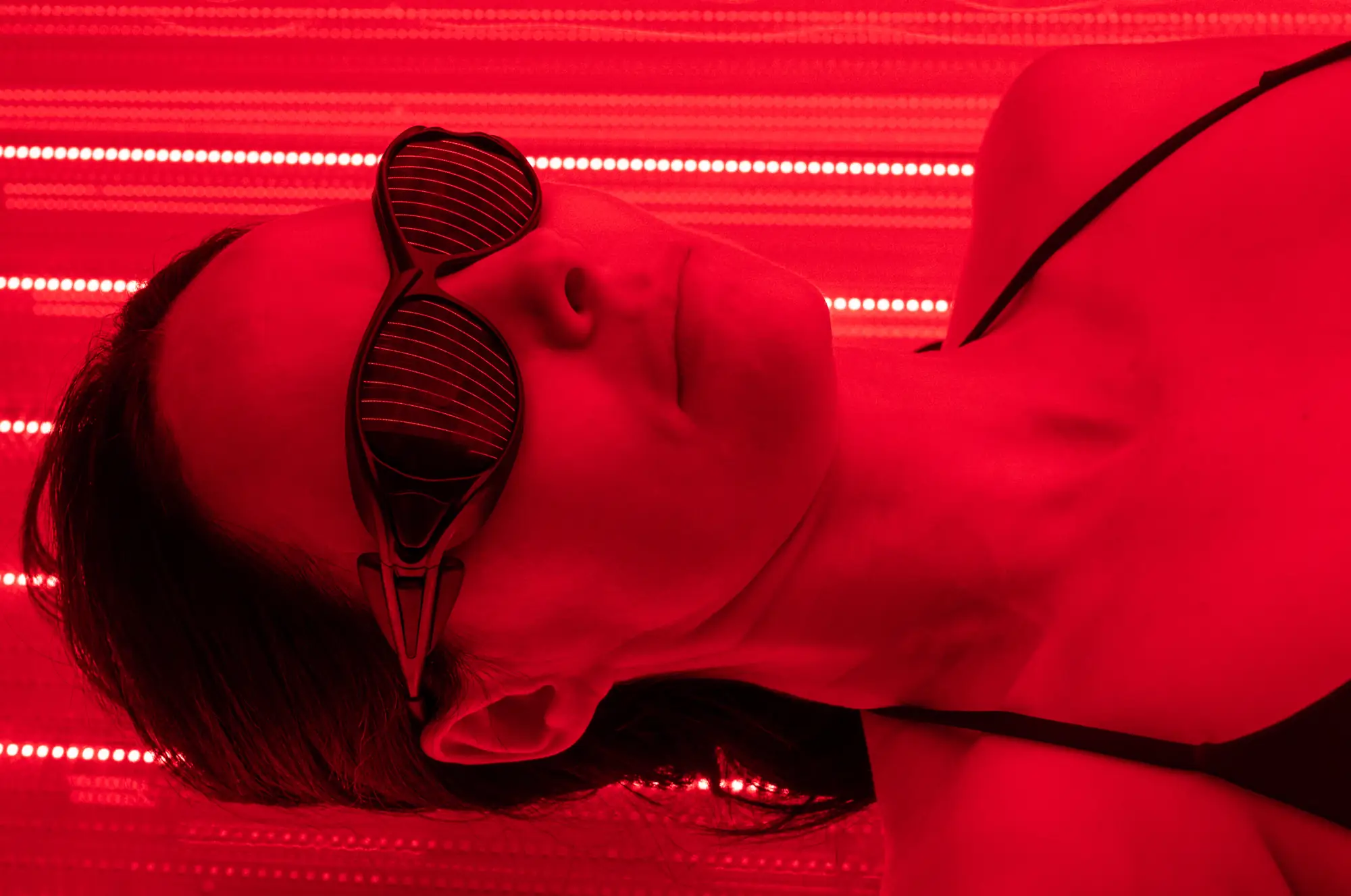 Close-up of a member's face in red light, wearing protective glasses