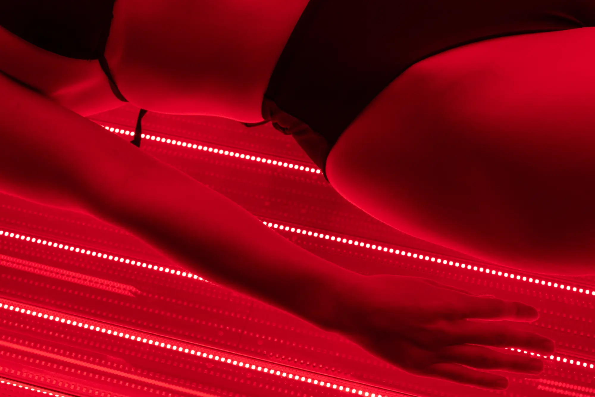 Close-up of a member's arm resting on the glowing panels of the red light bed