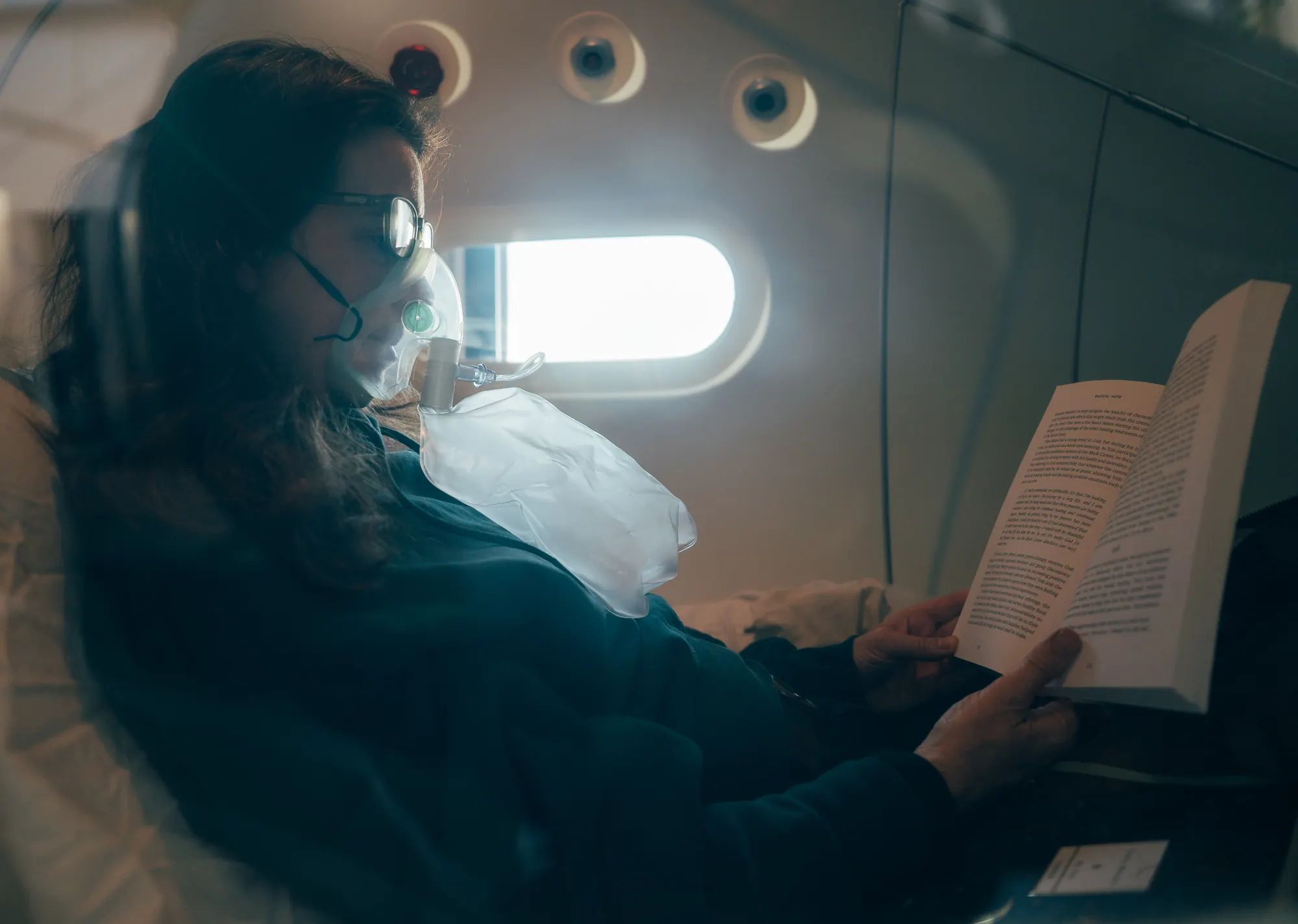 A member reading a book during a hyperbaric session, wearing an oxygen mask