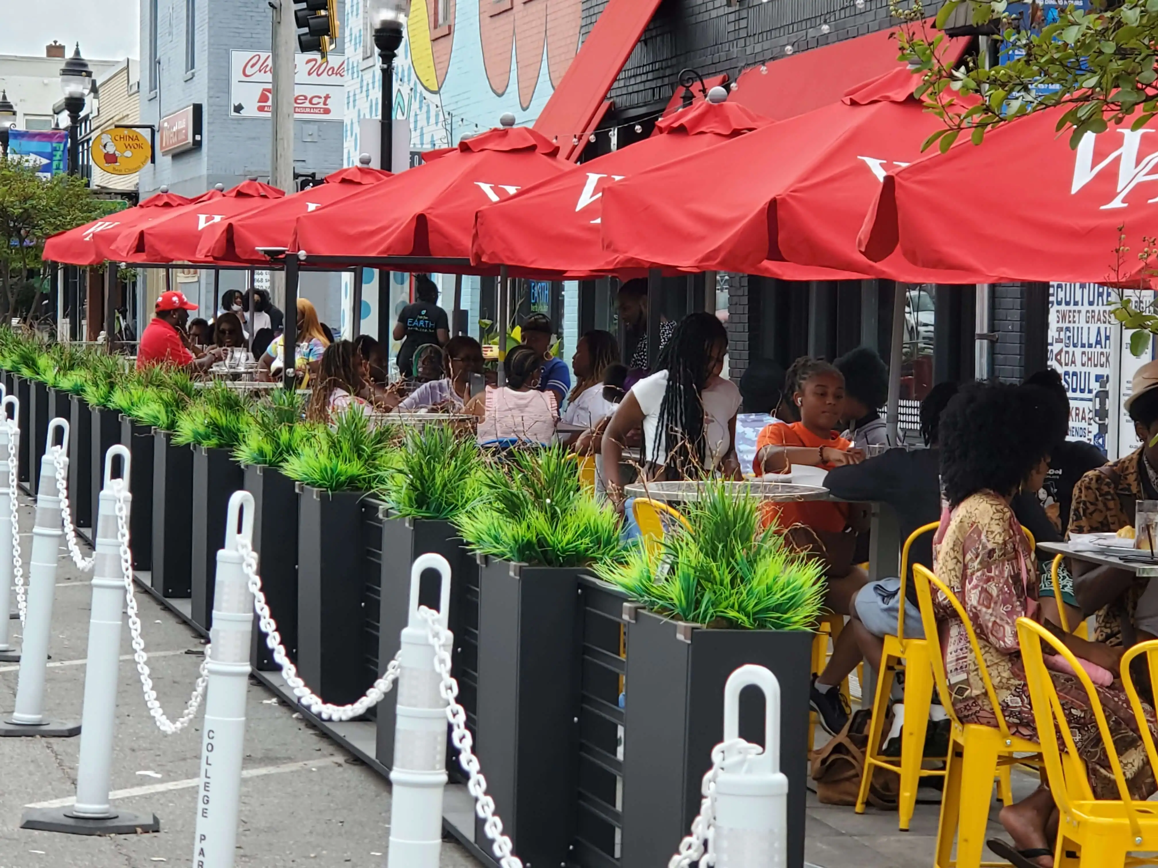 Diners eating beneath red umbrellas at the College Park parklet in Georgia.
