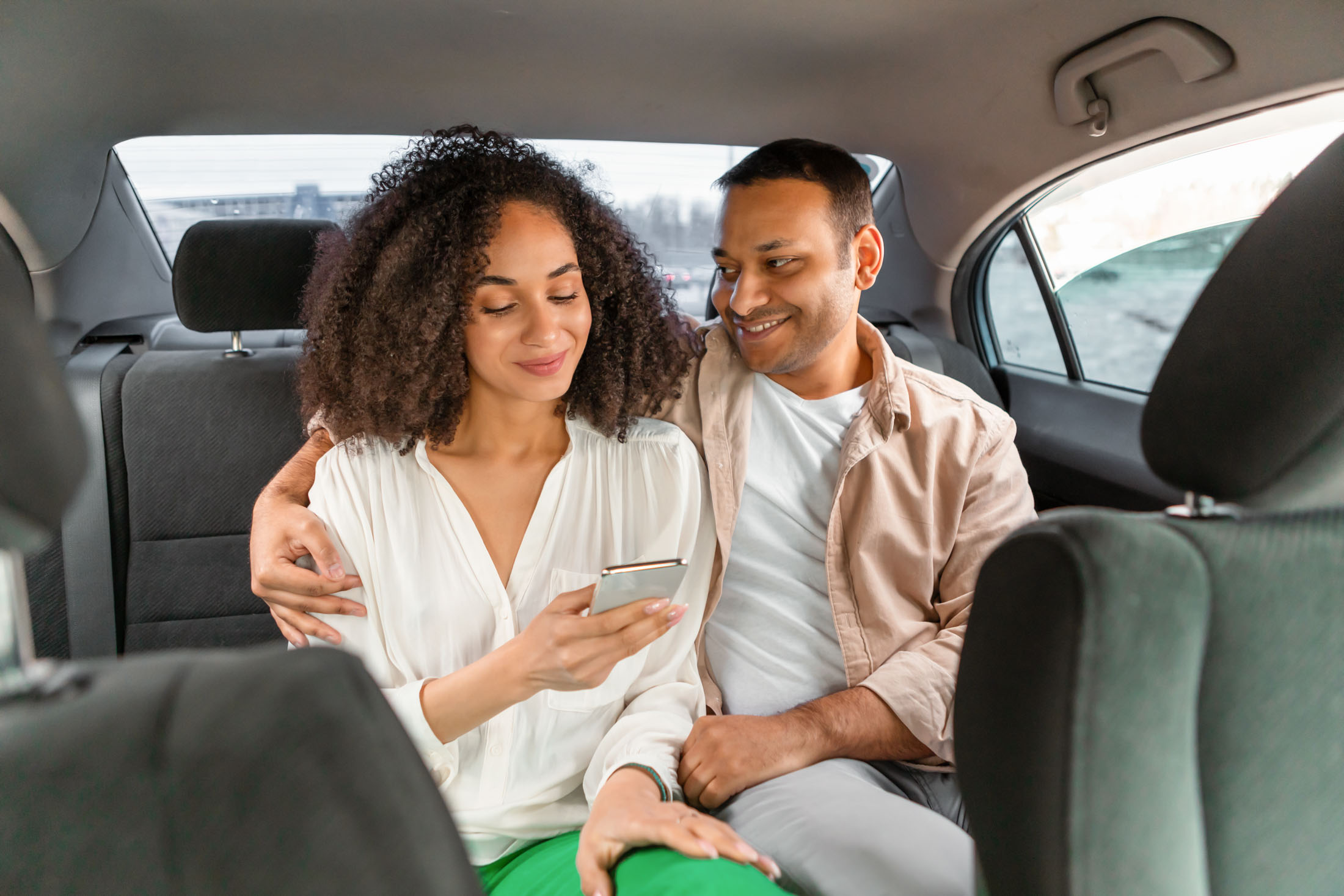 Couple in the back of a chauffeured car using a smartphone