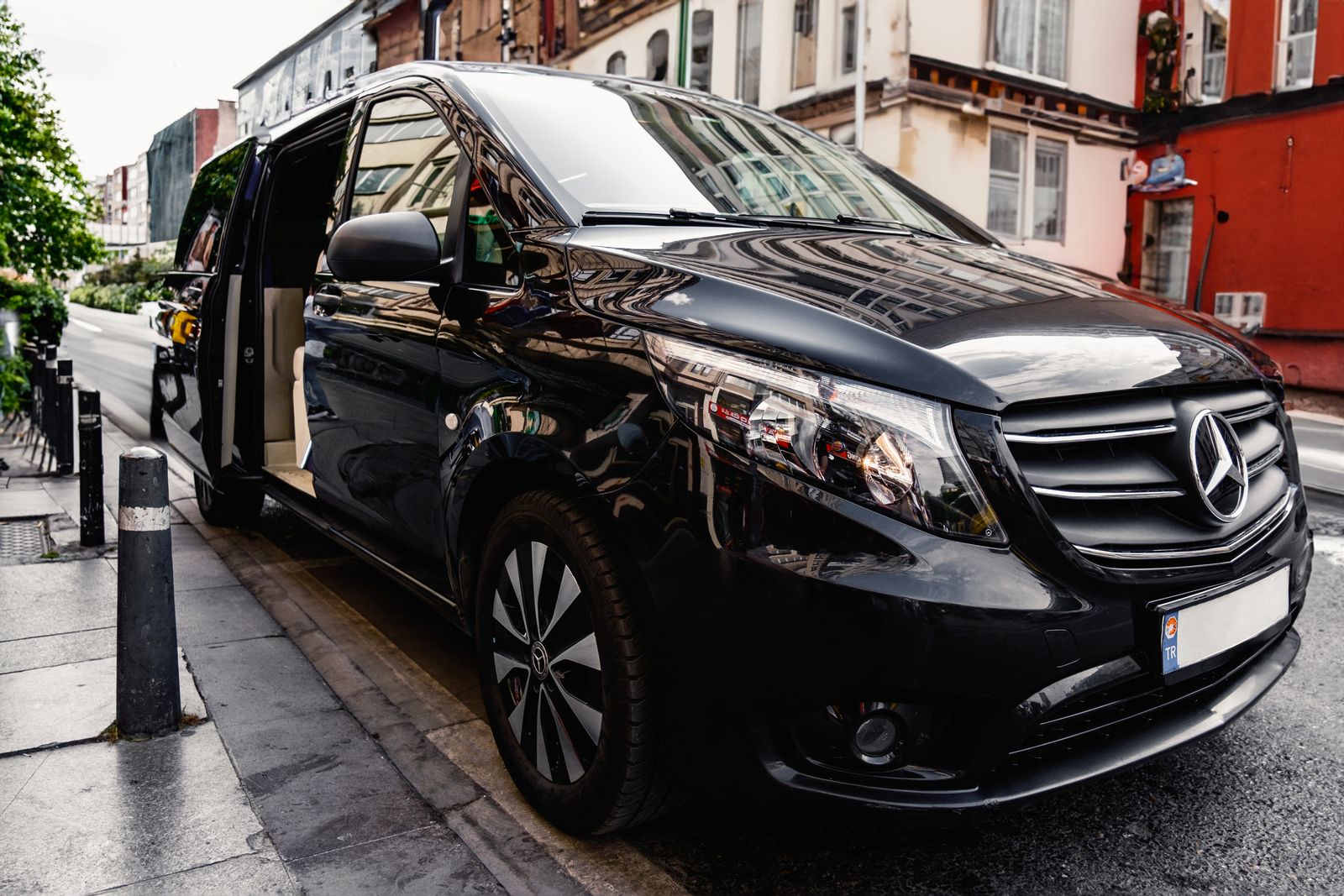 A black people mover parked at the kerb with its sliding door open