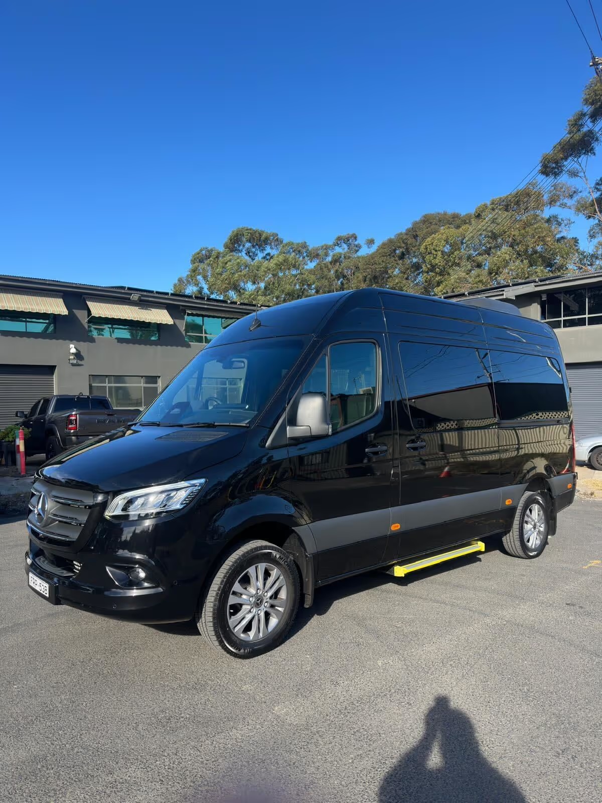 Black Mercedes-Benz Sprinter minibus parked in the sun