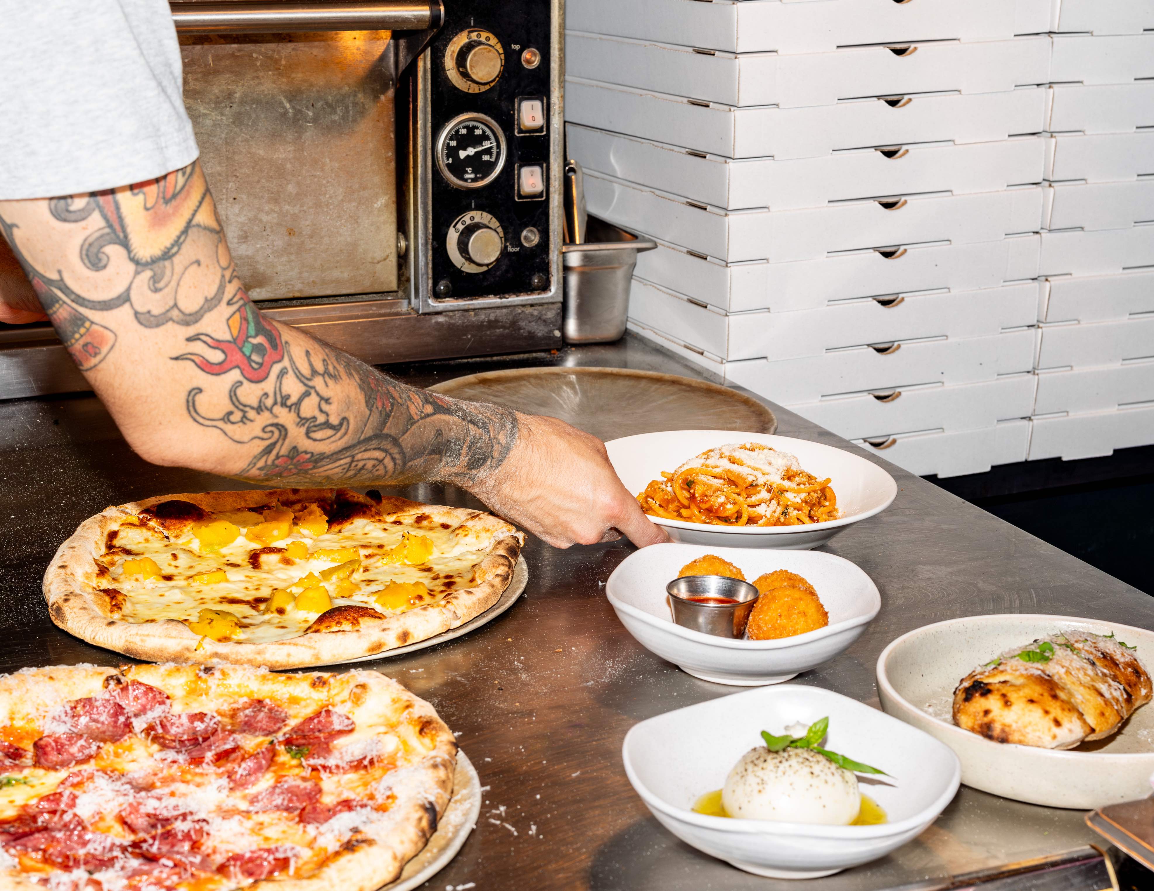 Person plating up pizza, pasta & burrata