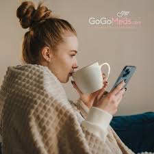 Woman looks at her phone while sipping a cup of coffee, GoGoMeds your new prescription for life 