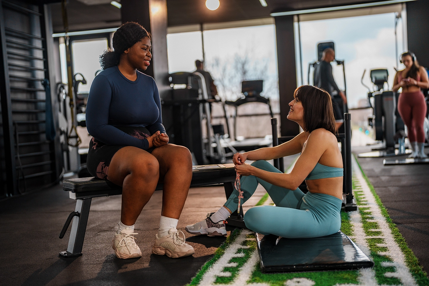 A person talking with a personal trainer at the gym, representing reflection and consistency in a wellness routine