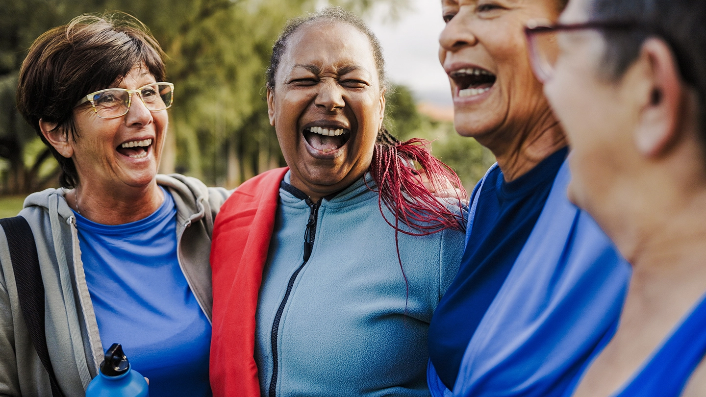 A woman sitting comfortably on a couch at home, reading, representing ease and everyday wellness
