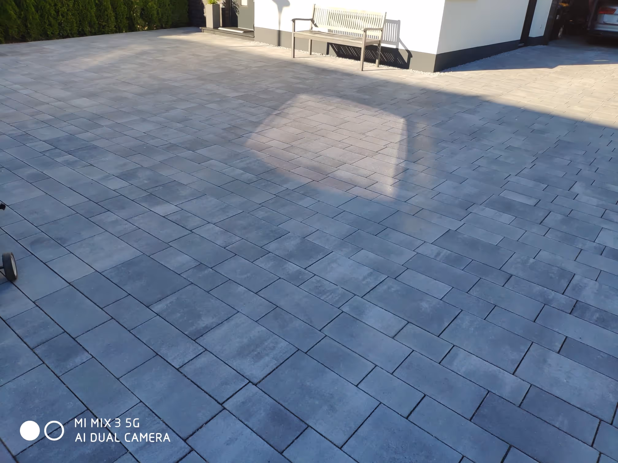 Großzügige Fläche aus modernen, grauen Rechteckpflastersteinen mit Sitzbank am Haus - Lindemann Bau GmbH