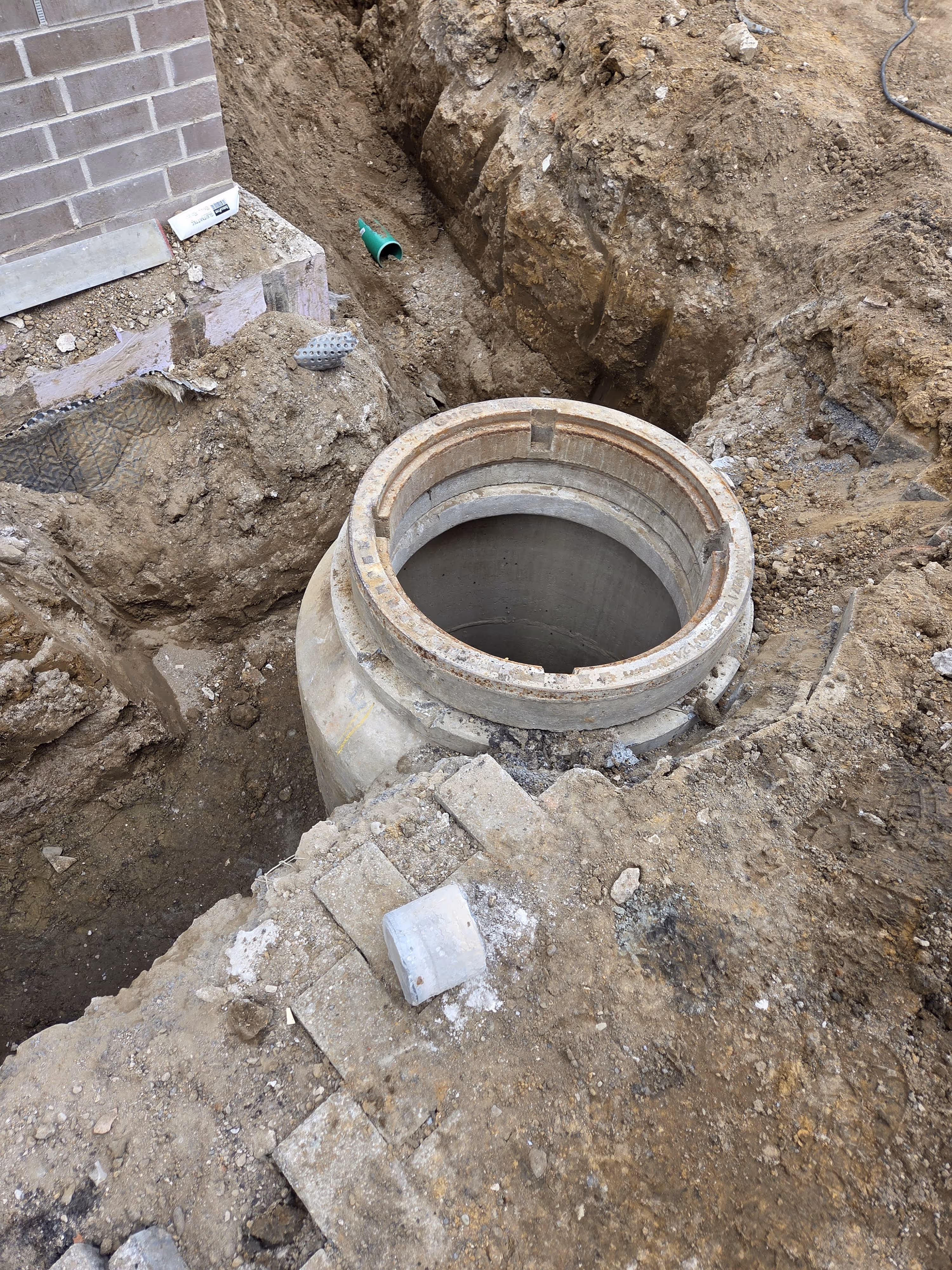 Blick in einen tiefen Betonschacht für Regenwasserleitungen in einer Baugrube - Lindemann Bau GmbH