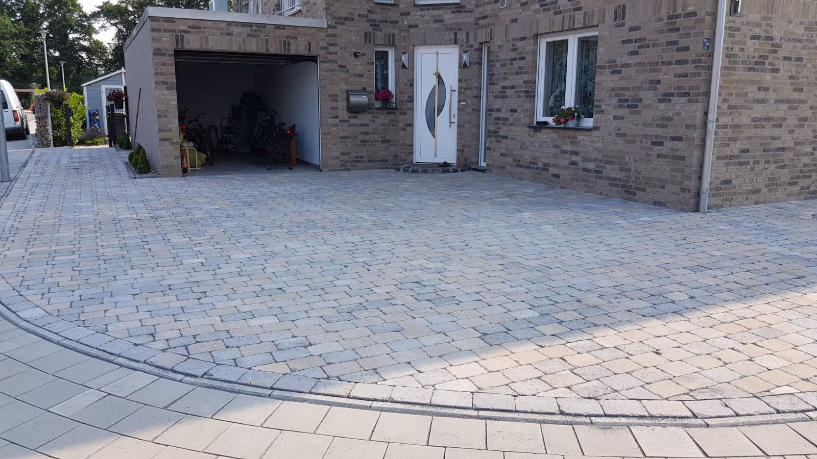 Fertiggestellte Einfahrt aus hellem, buntem Kopfsteinpflaster mit sauberer Randeinfassung - Lindemann Bau GmbH