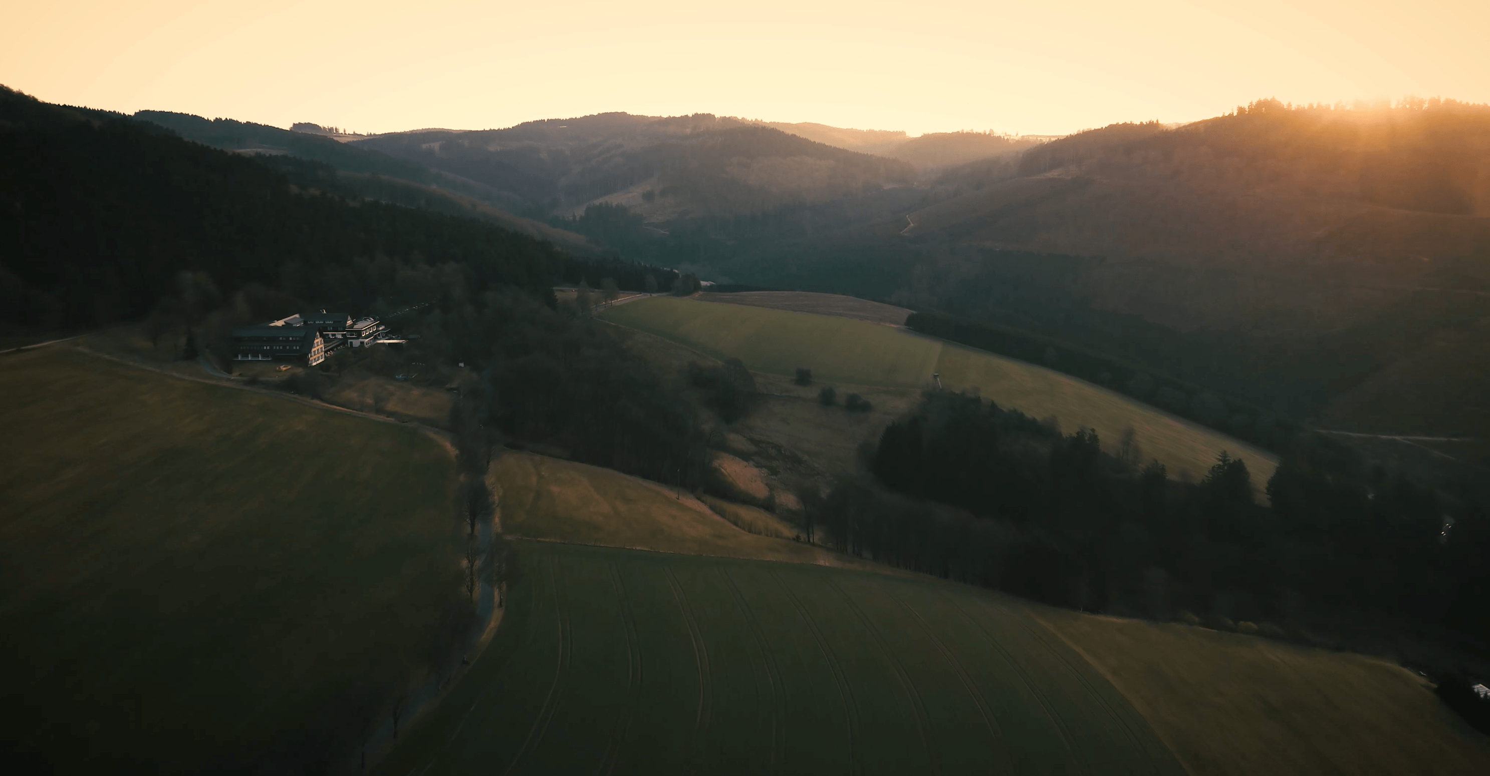 Verschneiter Tannenwald auf Hügeln unter einem bewölkten Himmel.