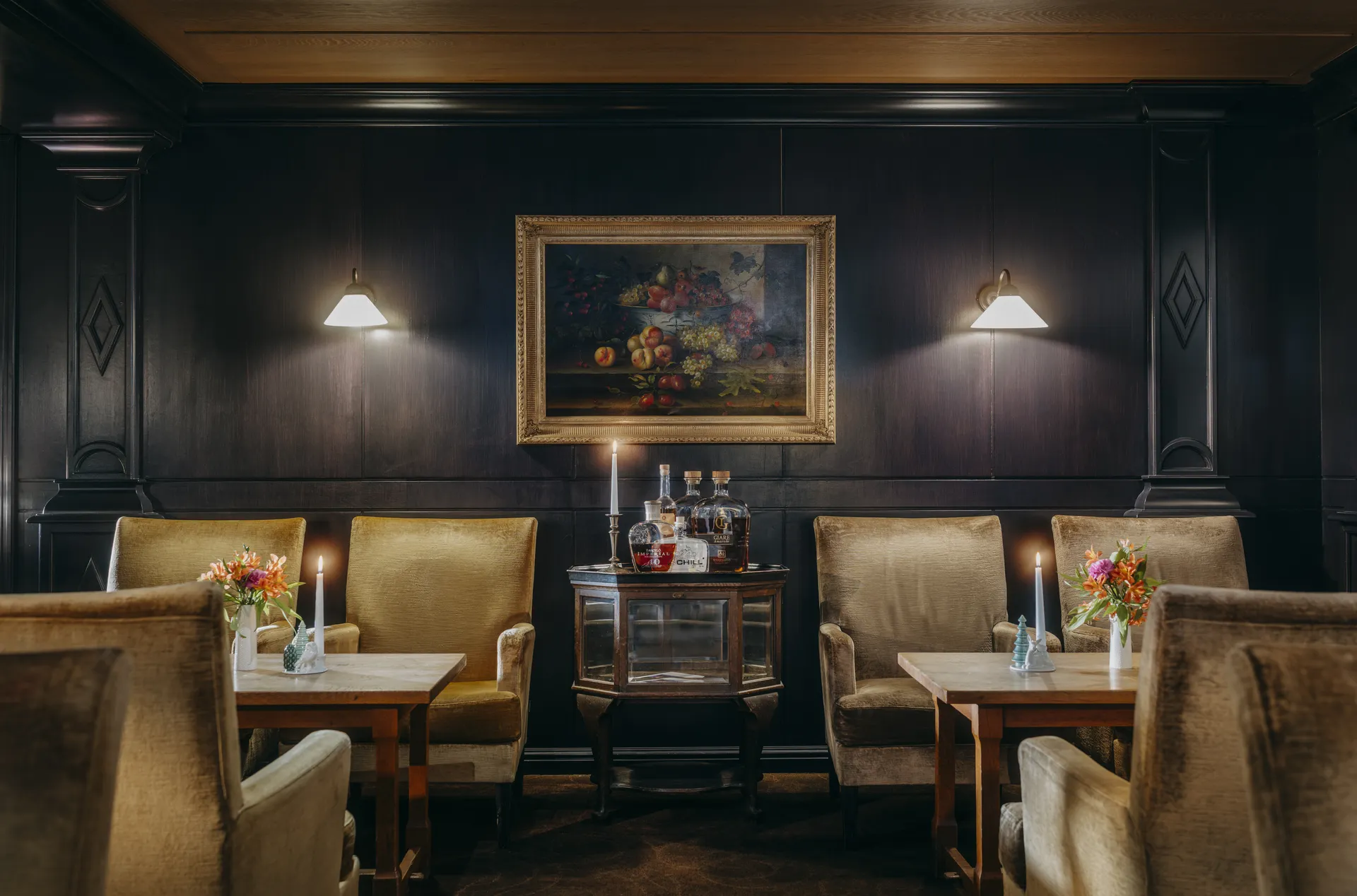Eleganter Esstisch in einem Restaurant mit weißen Tischdecken, gefalteten Servietten, Weingläsern und einer Blumenvase, umgeben von gemusterten Polstersesseln.