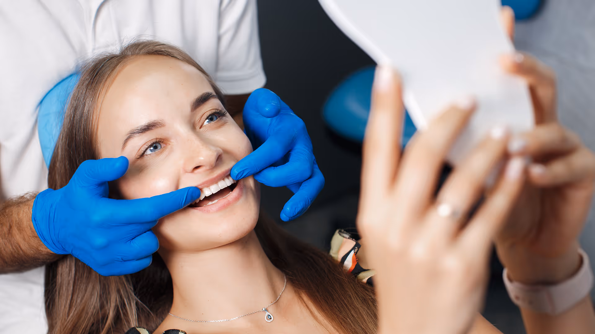 Zahnärztin mit blauen Handschuhen untersucht Lächeln des Patienten