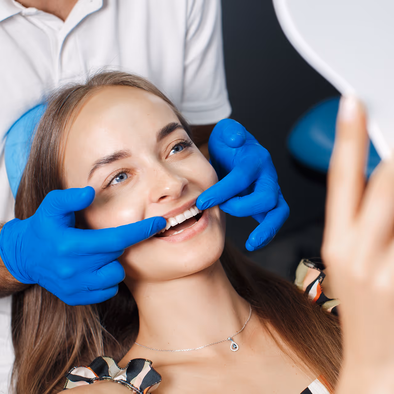 Zahnmedizinische Untersuchung mit blau behandschuhten Händen in Zahnarztpraxis