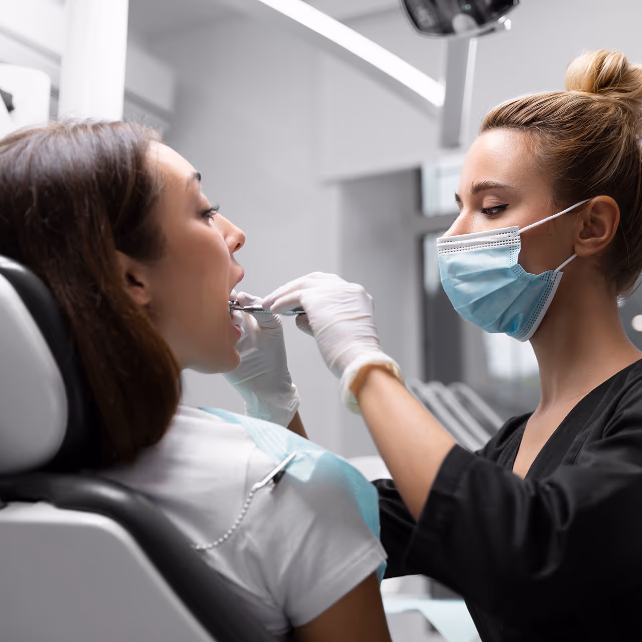 Zahnärztin untersucht Patientin während einer professionellen Zahnbehandlung