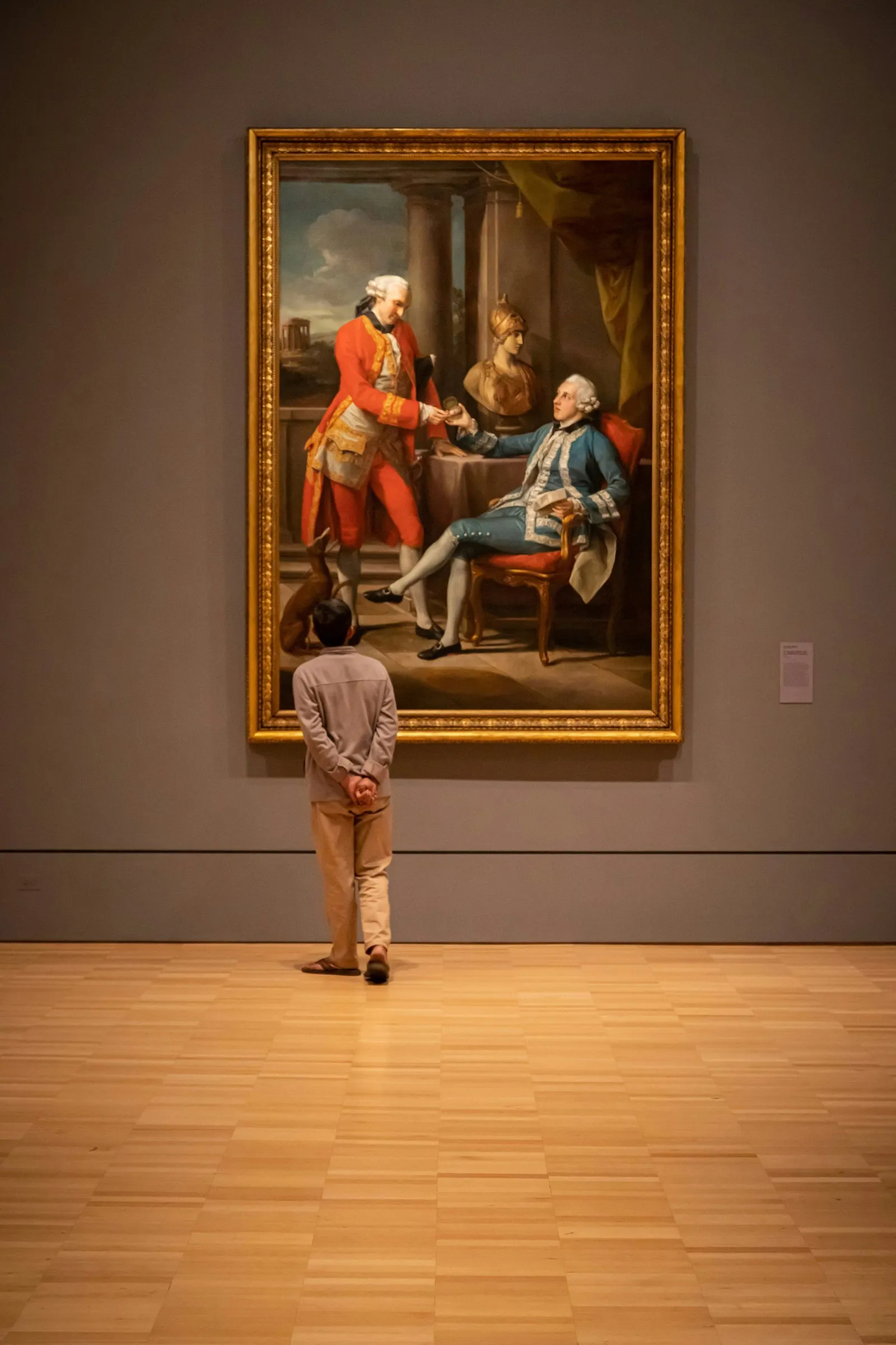 A person observing a large classical painting in a museum