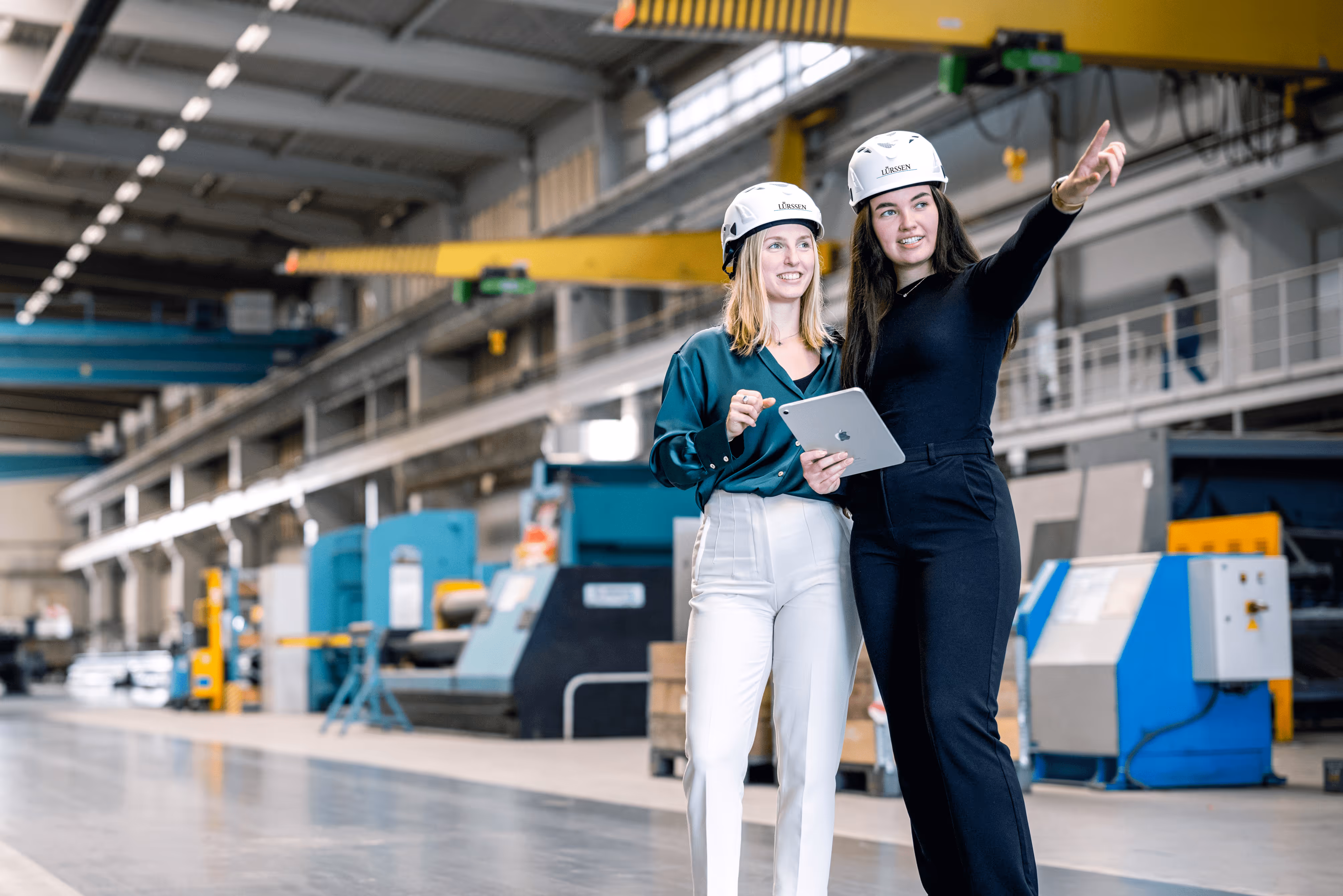 Paar Frauen mit Helmen in einer Fabrikhalle