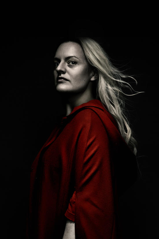 Profile portrait of a woman with long blonde hair wearing a red cloak against a dark background.