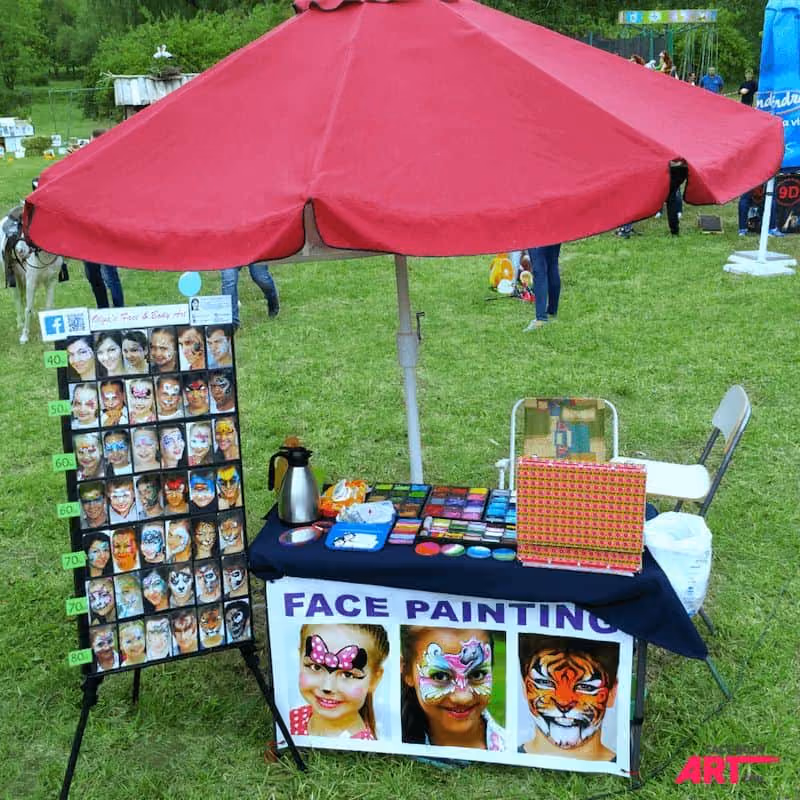 an image of a face painting booth with a red sun umbrella