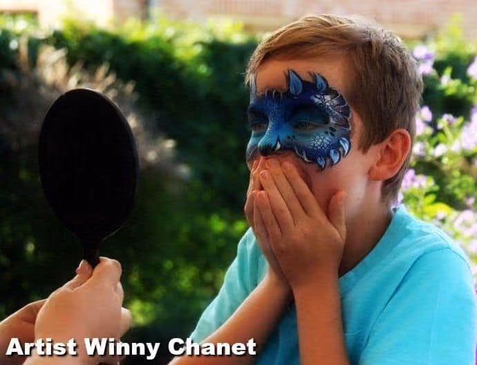 a boy looking at his face paint design in the mirror astonished