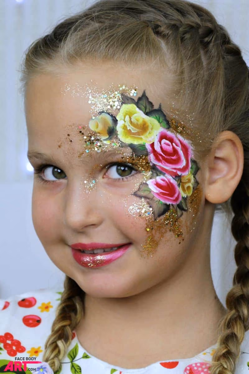girl with a yellow and pink rose face paint around her left eye looking at the camera