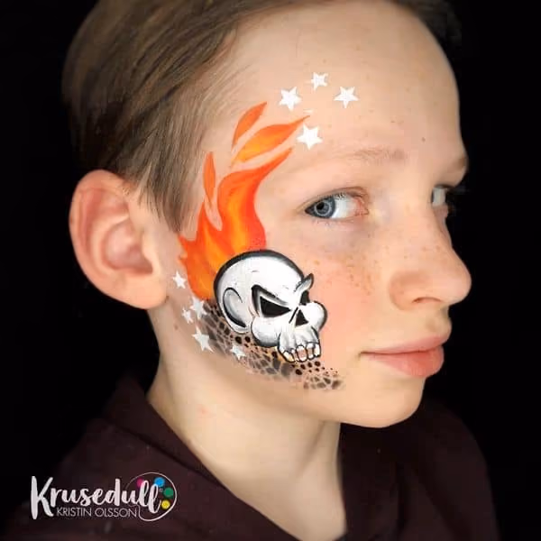 boy looking ah the camera from a side. he has a cartoon burning skull with stars painted on his face