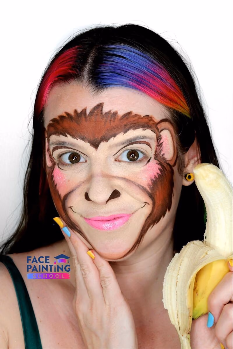 a girl with an compleated monkey face paint design holding a banana