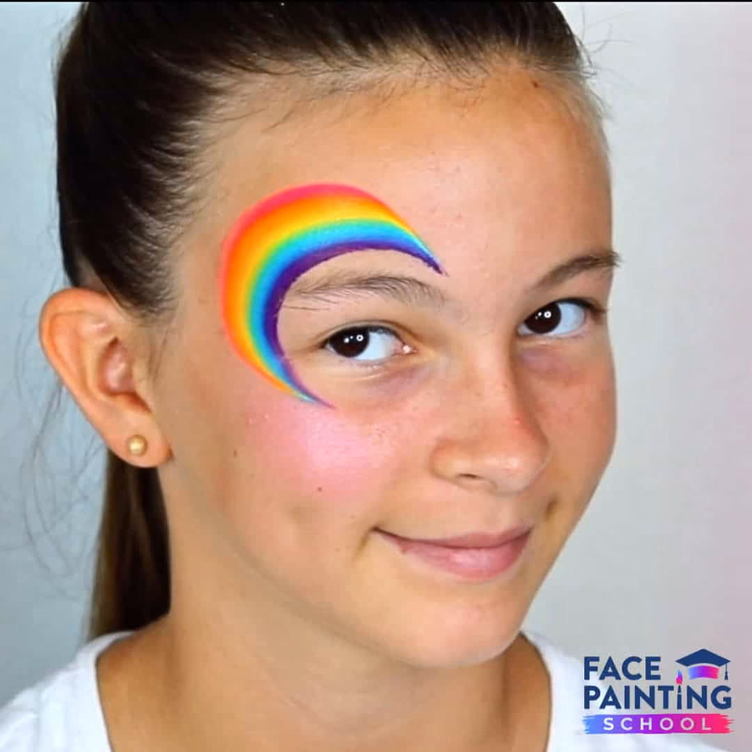a girl with a rose face paint on her right cheekbone and a rainbow face paint around her eye