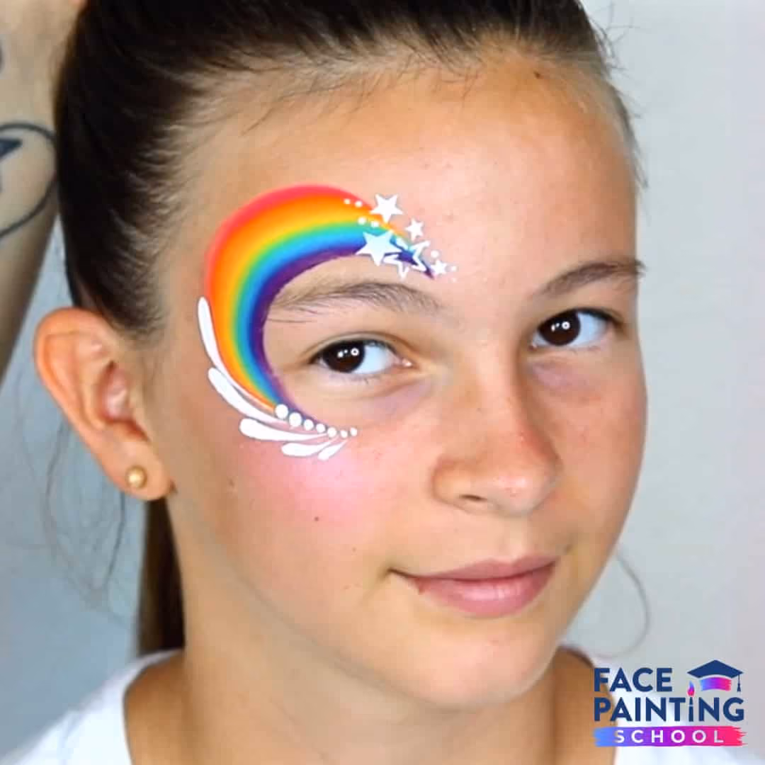 a girl with a rainbow face paint around her eye with added stars and a splash effect