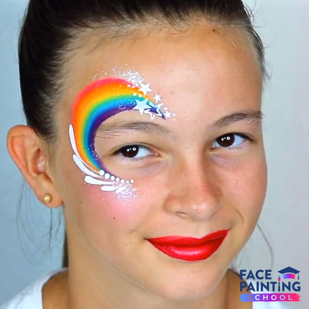 a girl with a rainbow face paint around her eye and red lipstick