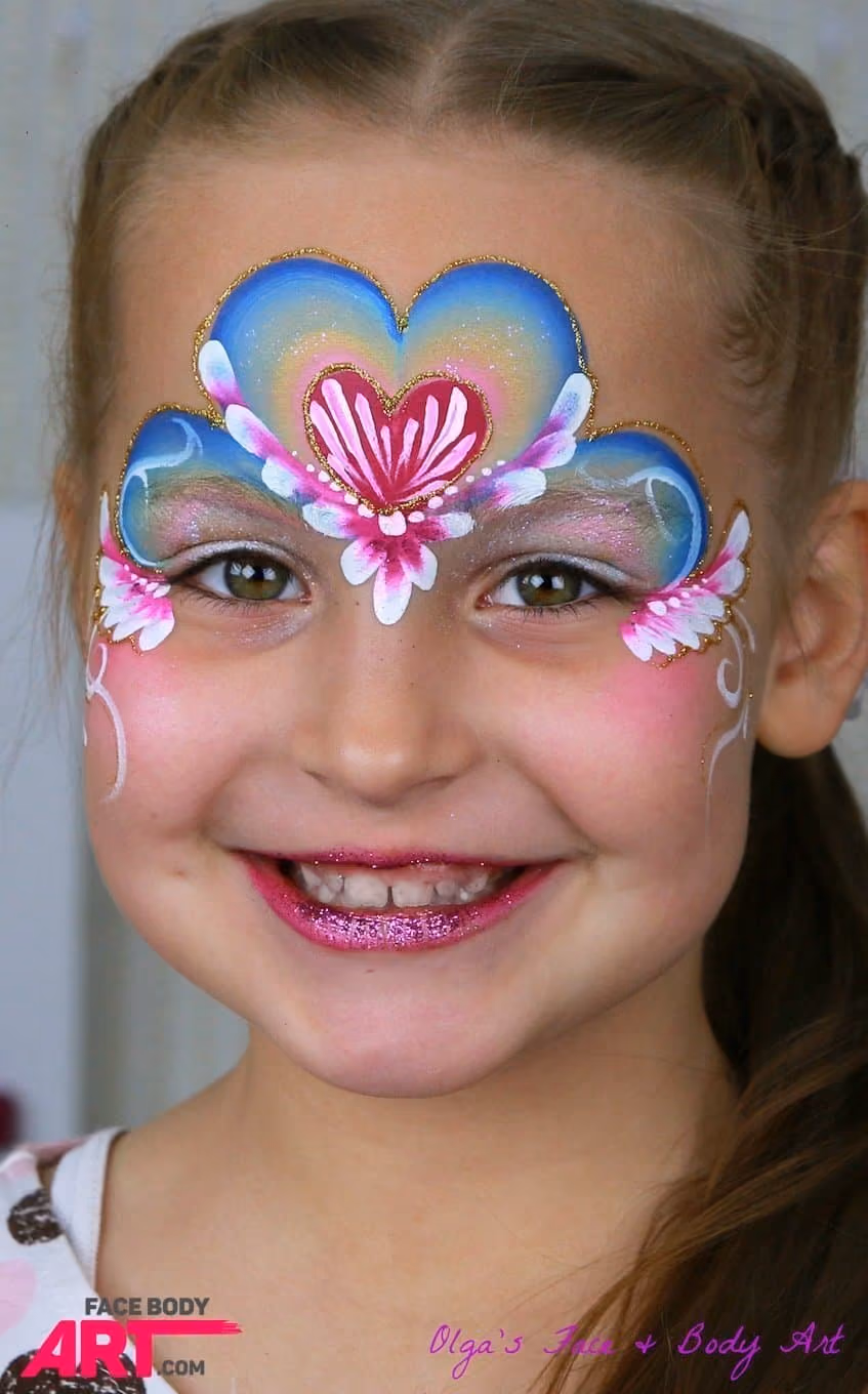 smiling girl looking at the camera wtih a blue and pink heart princess face paint