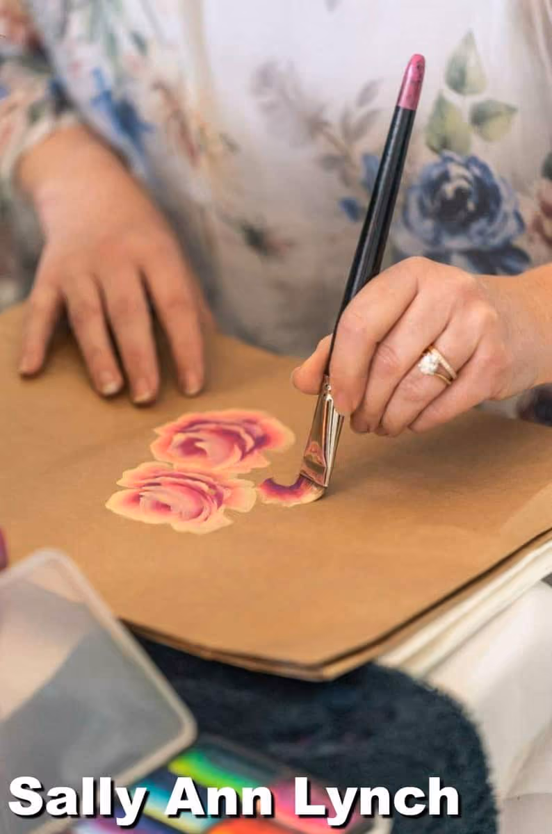 an image of a woman practicing painting roses on a cardboard