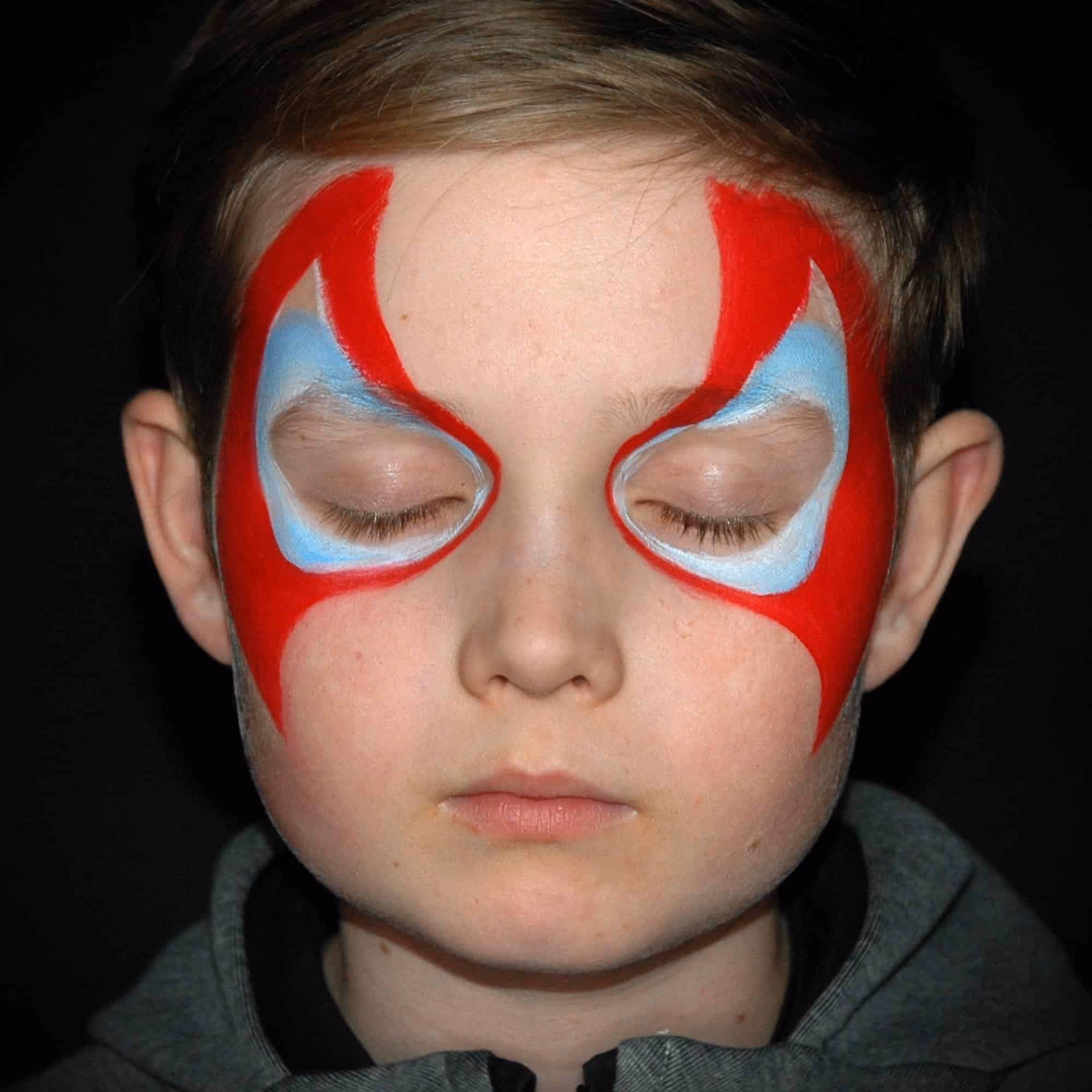 a boy with a base of a spiderman face paint around his eyes