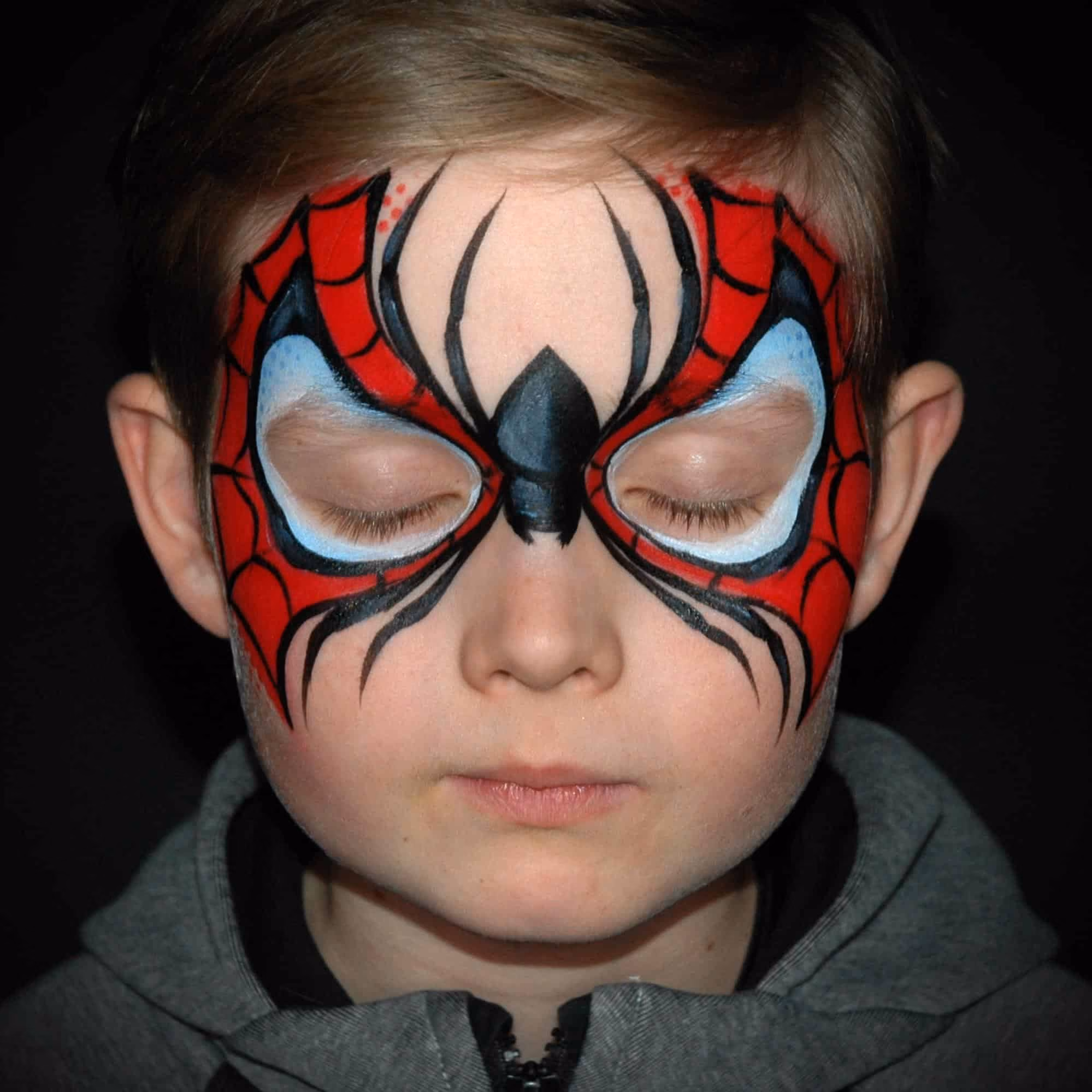 a boy with a finished spiderman face paint design