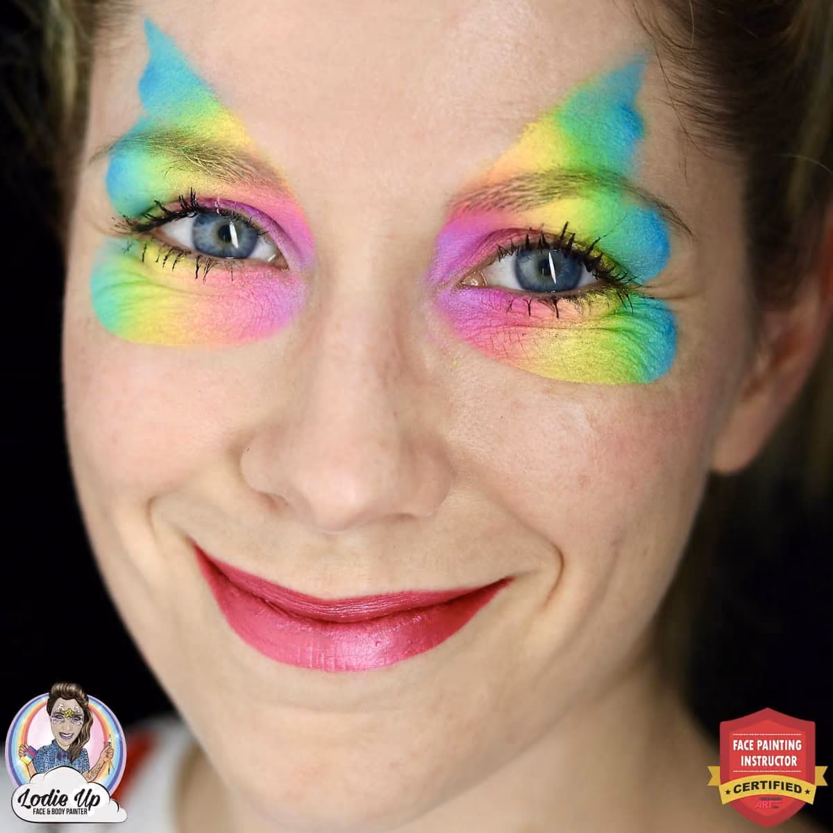 a woman with a base of a rainbow butterfly face paint on and around her eyes