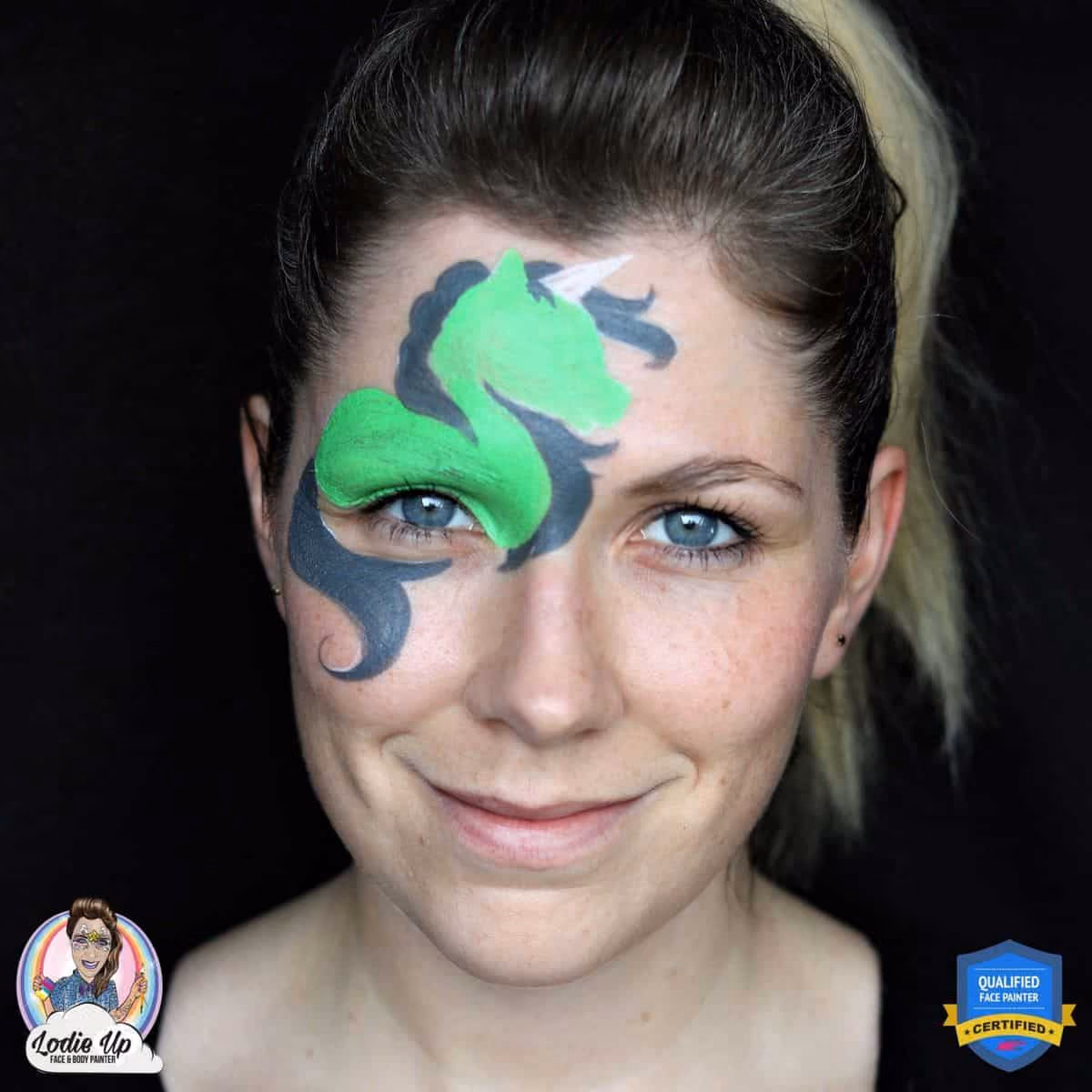 a woman with a green unicorn face paint base above her right eye