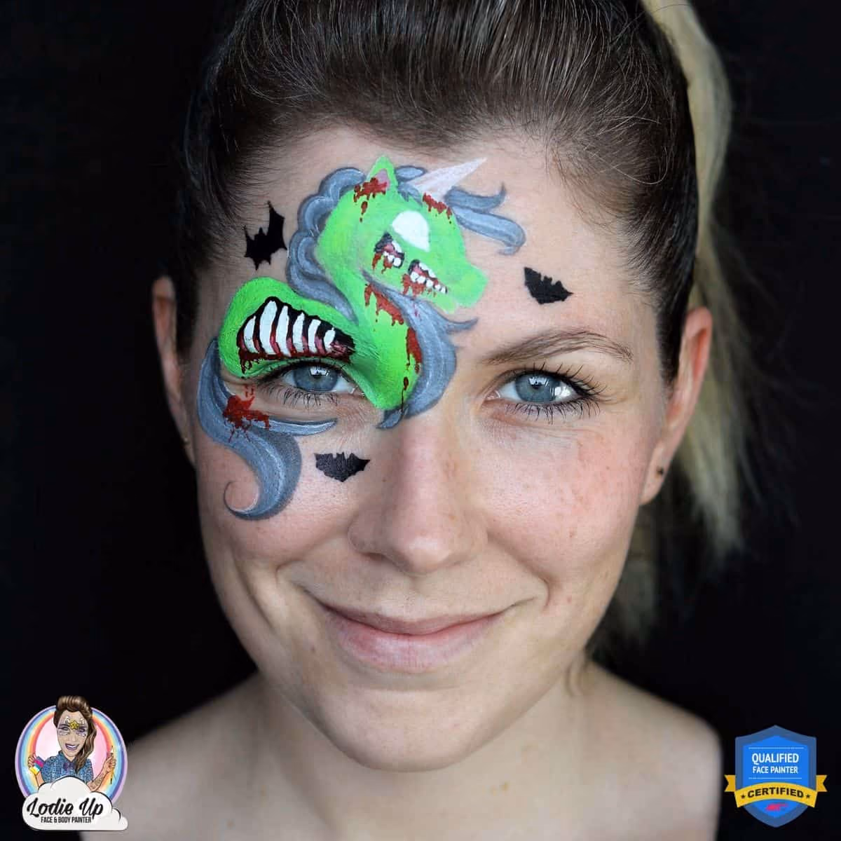 woman with a base green zombie unicorn face paint around her right eye. the unicorn has a undetailed eye.