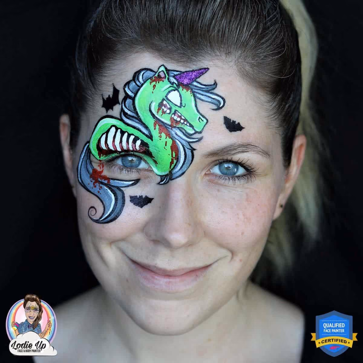 a woman with a compleated green zombie unicorn face painting above her right eye