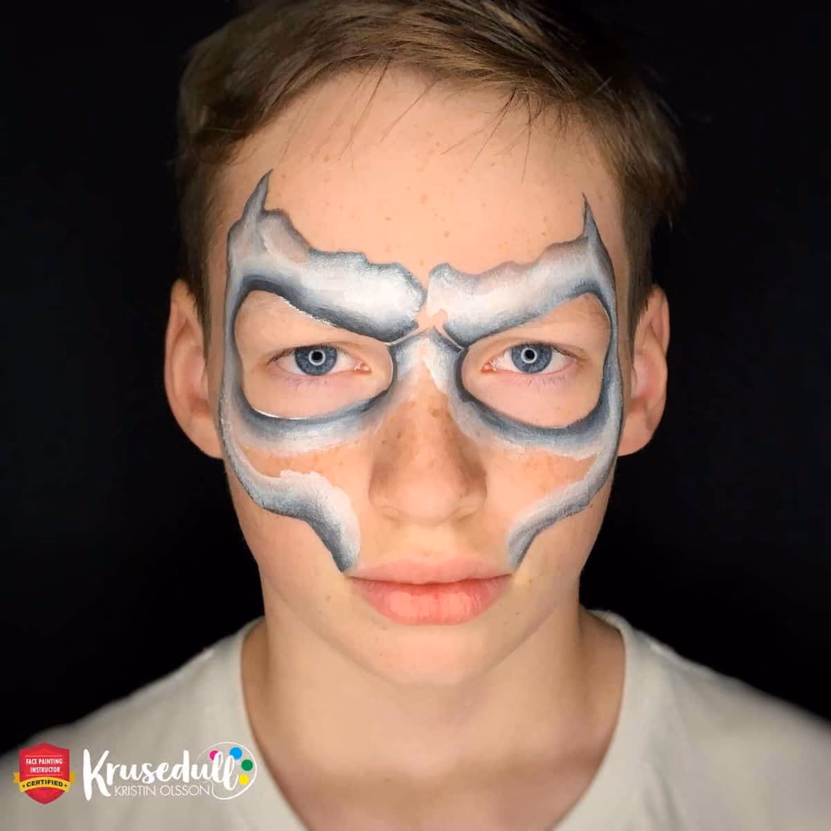 a boy with an uncomplete skull face paint around his eyes