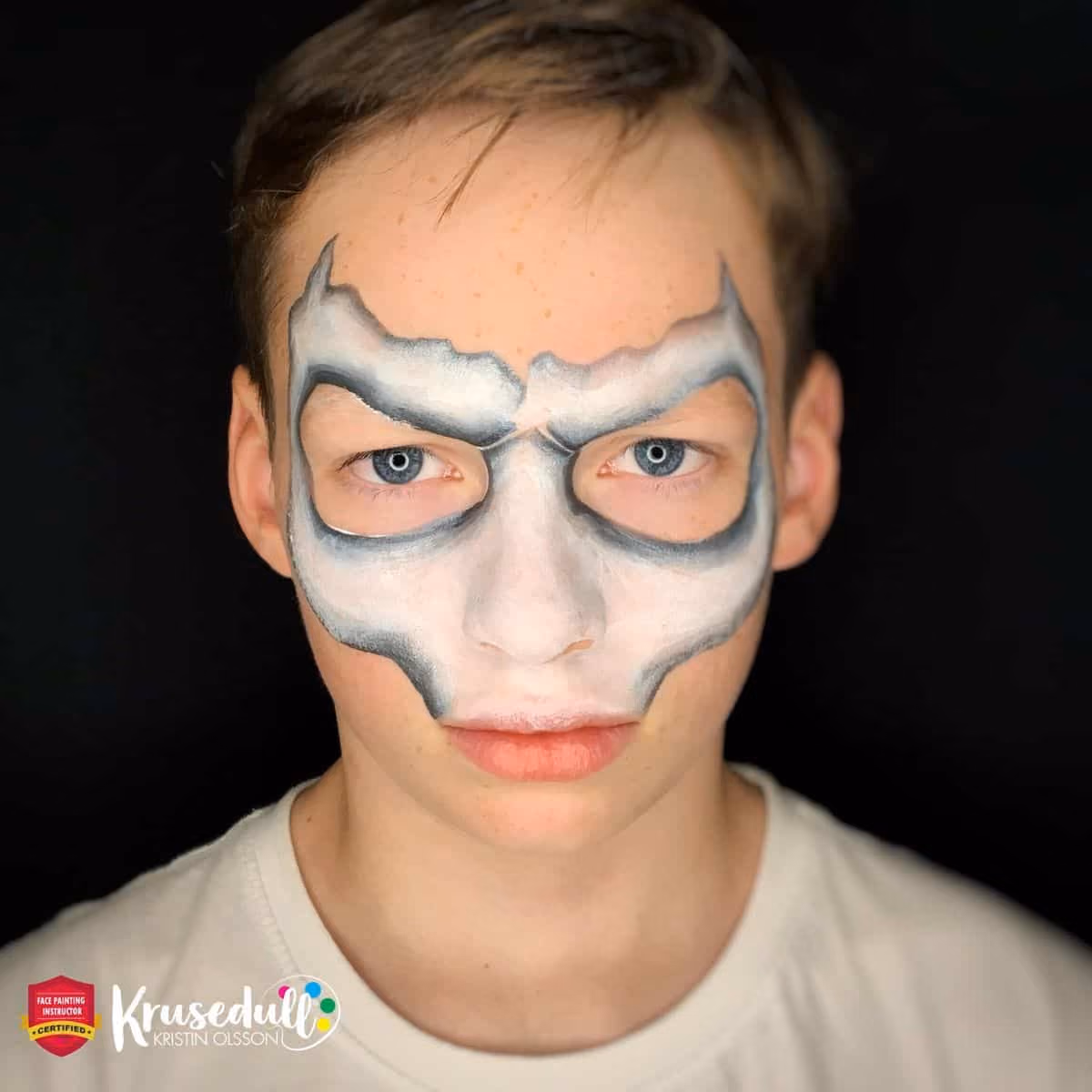 a boy with an uncomplete skull face paint around his face except the forehead