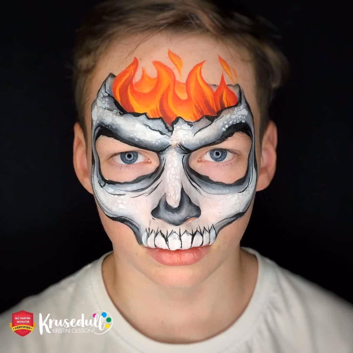 a boy looking at the camera with a finished design of a skull face painting