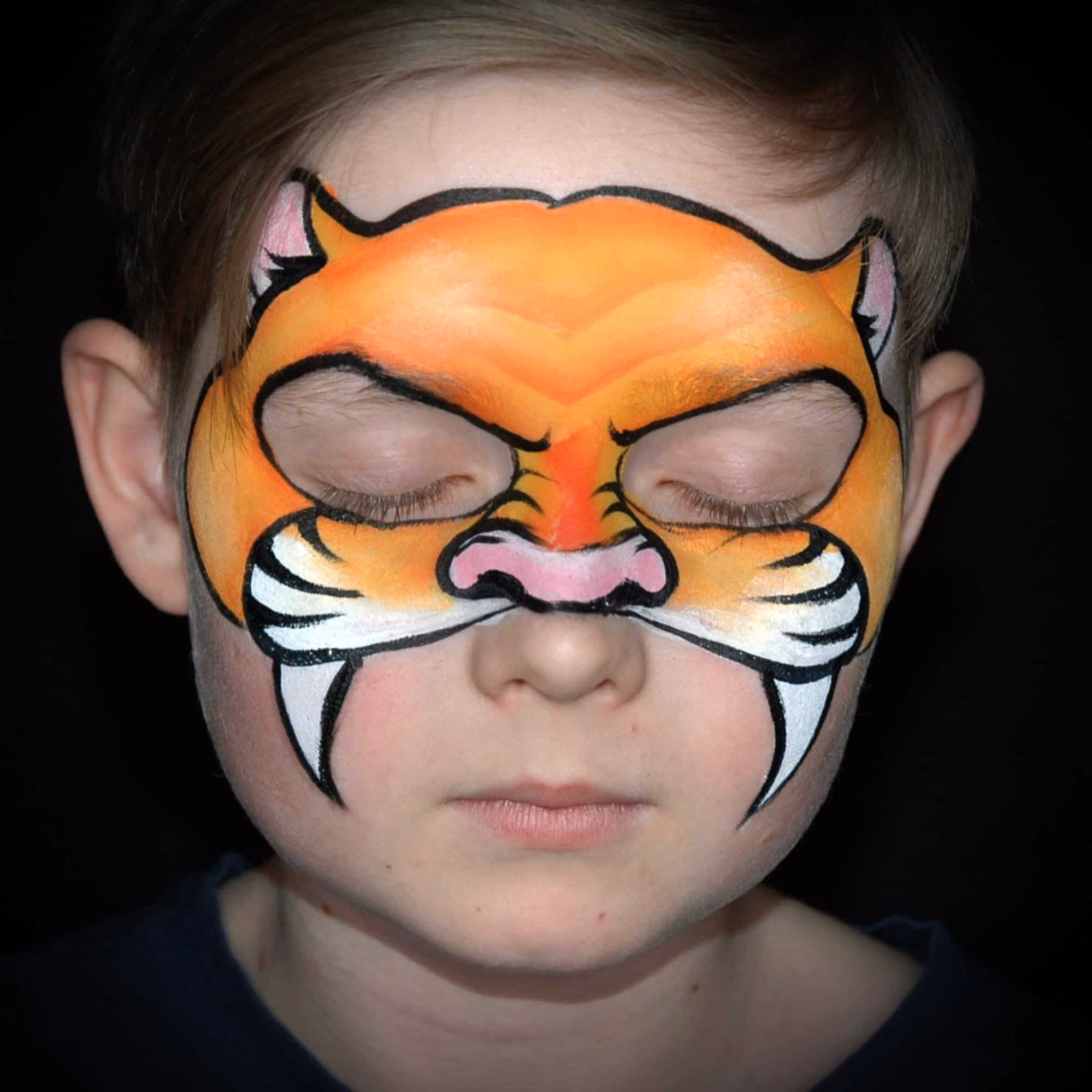 a boy with a sharp black overlay of a tiger face paint filled with the orange color with two fangs