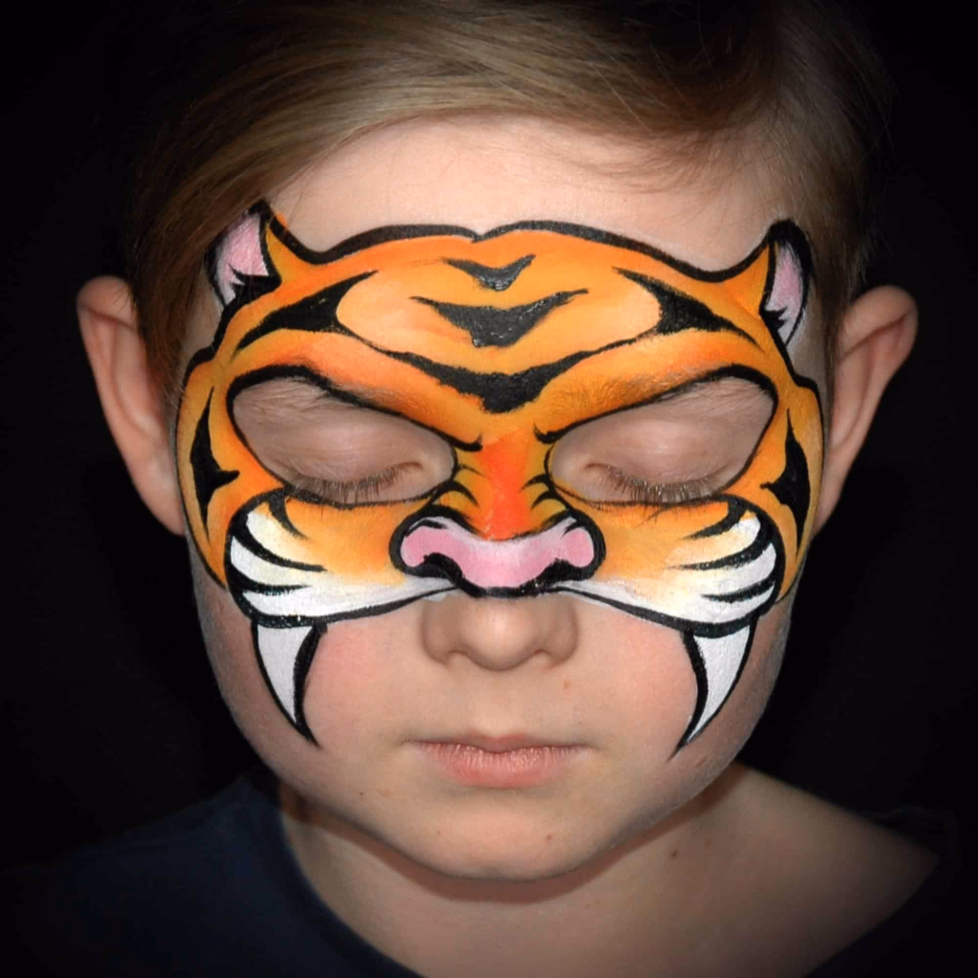 a boy with a compleated tiger face paint mask